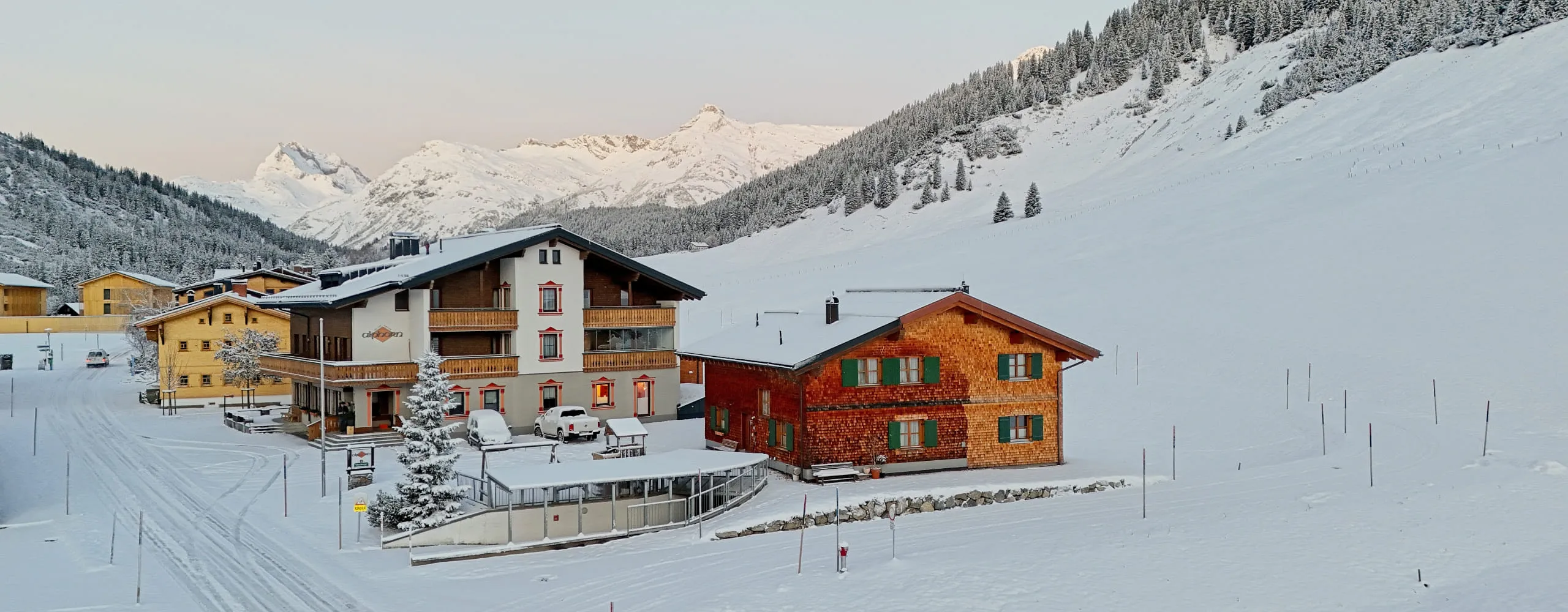 Blick auf Gasthof Alphorn im Winter mit schneebedeckten Bergen im Hintergrund