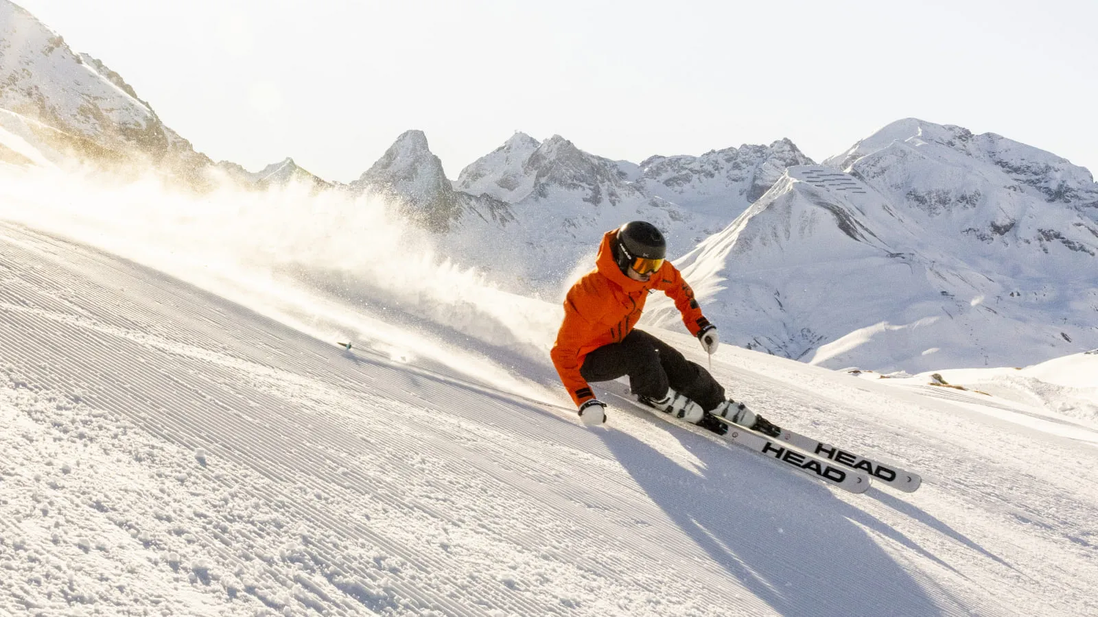 Skifahrer in orangeem Outfit auf einer Piste in Lech Zürs