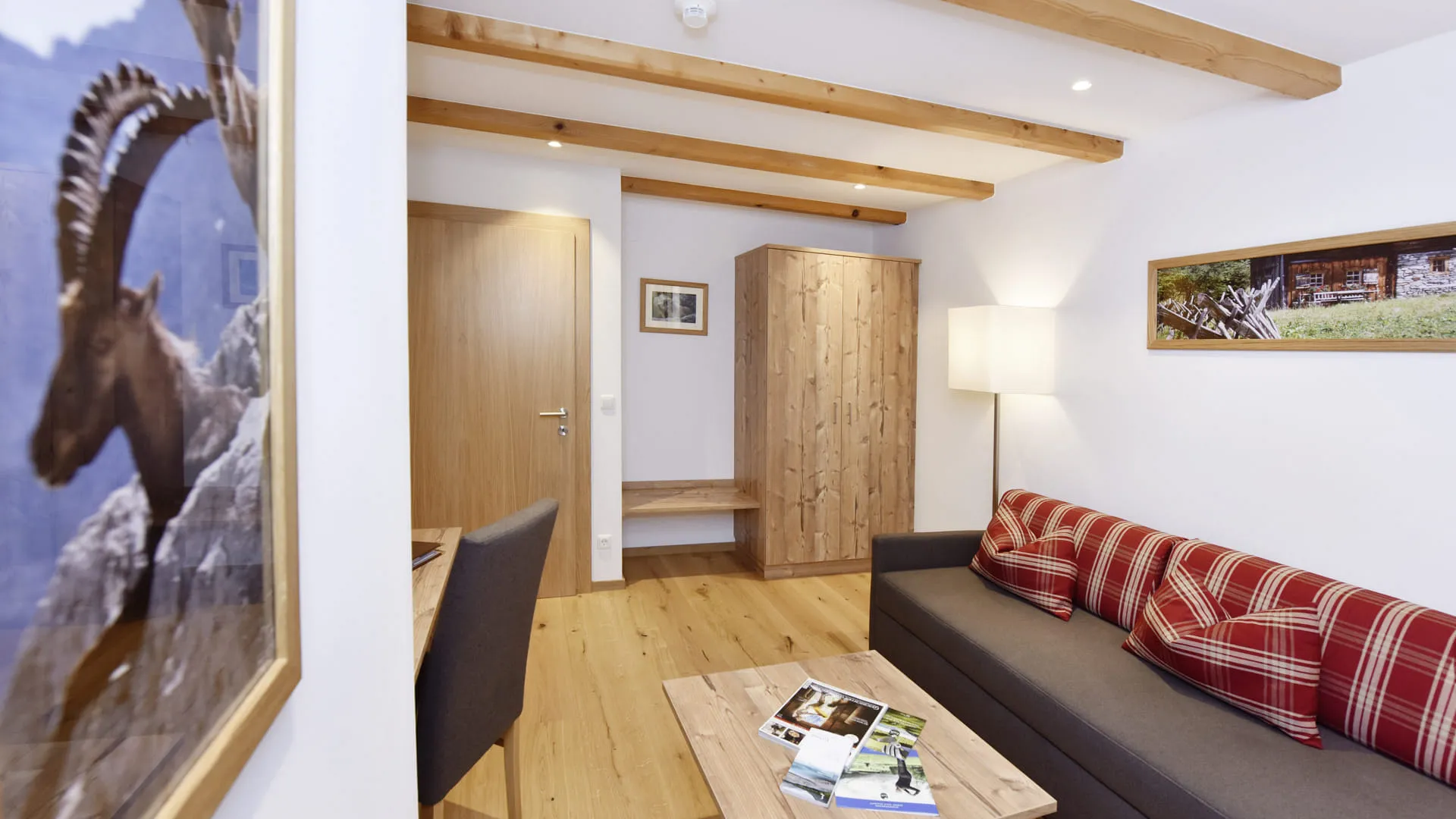 Wohnbereich mit Holzdetails, Couch, Tisch und gegenüberliegender Tür.