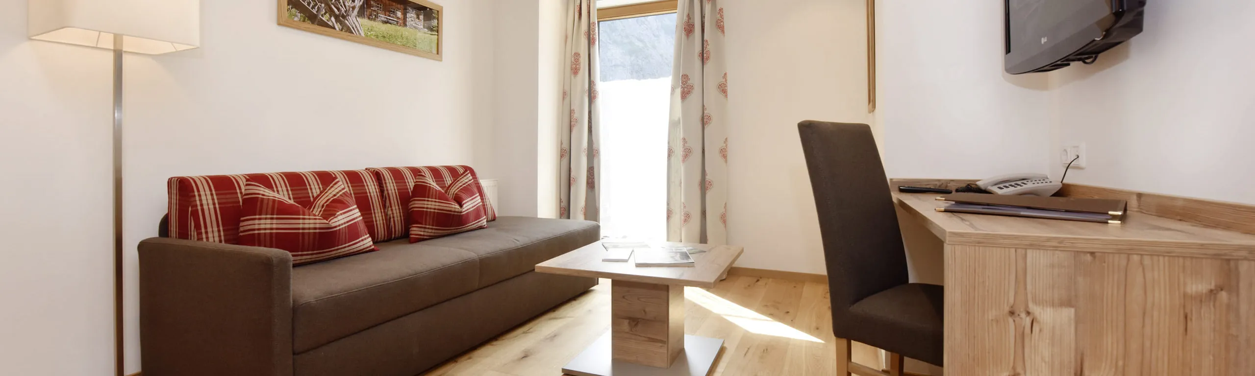 Ein gemütlicher Raum mit Sofa, Tisch, Stuhl und Fernseher
