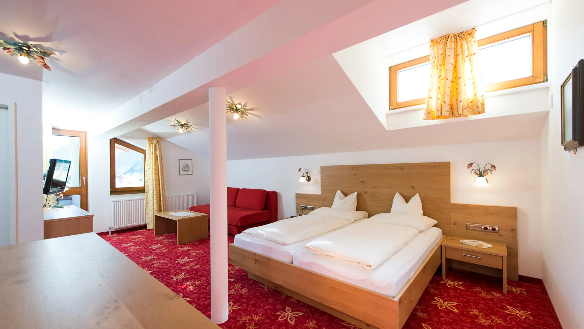 Helles Zimmer mit zwei Betten, rotem Sessel und Fenstern.
