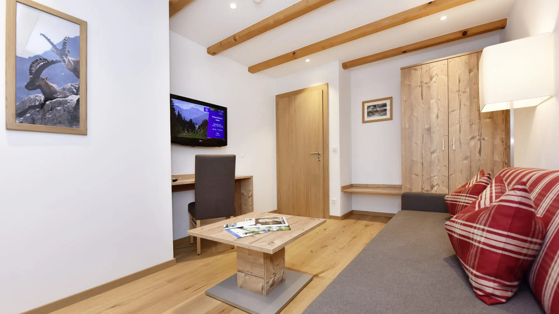 gemütlicher Raum mit Holzdecken, TV und kariertem Sofa