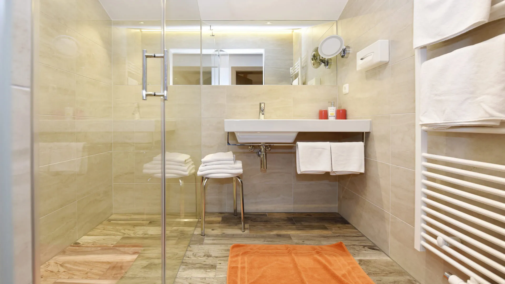 modernes Badezimmer mit Dusche, Waschbecken und Handtüchern