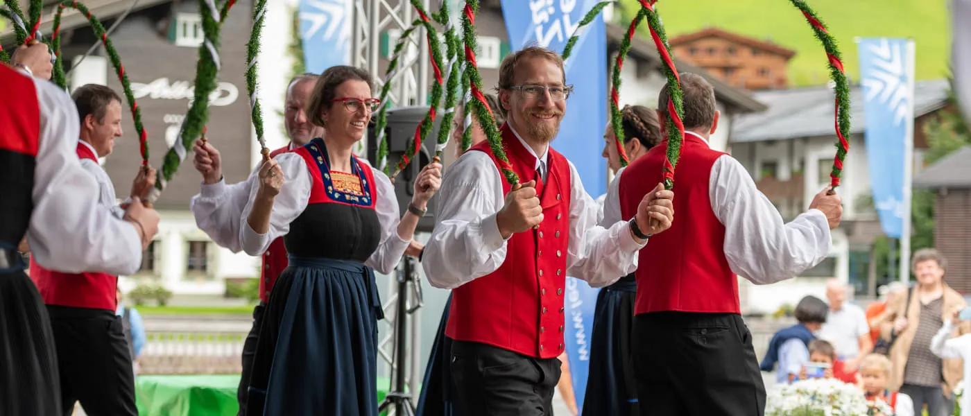 Tanzende Personen in traditionellen Kleidern beim Musikantentag Lech 2023