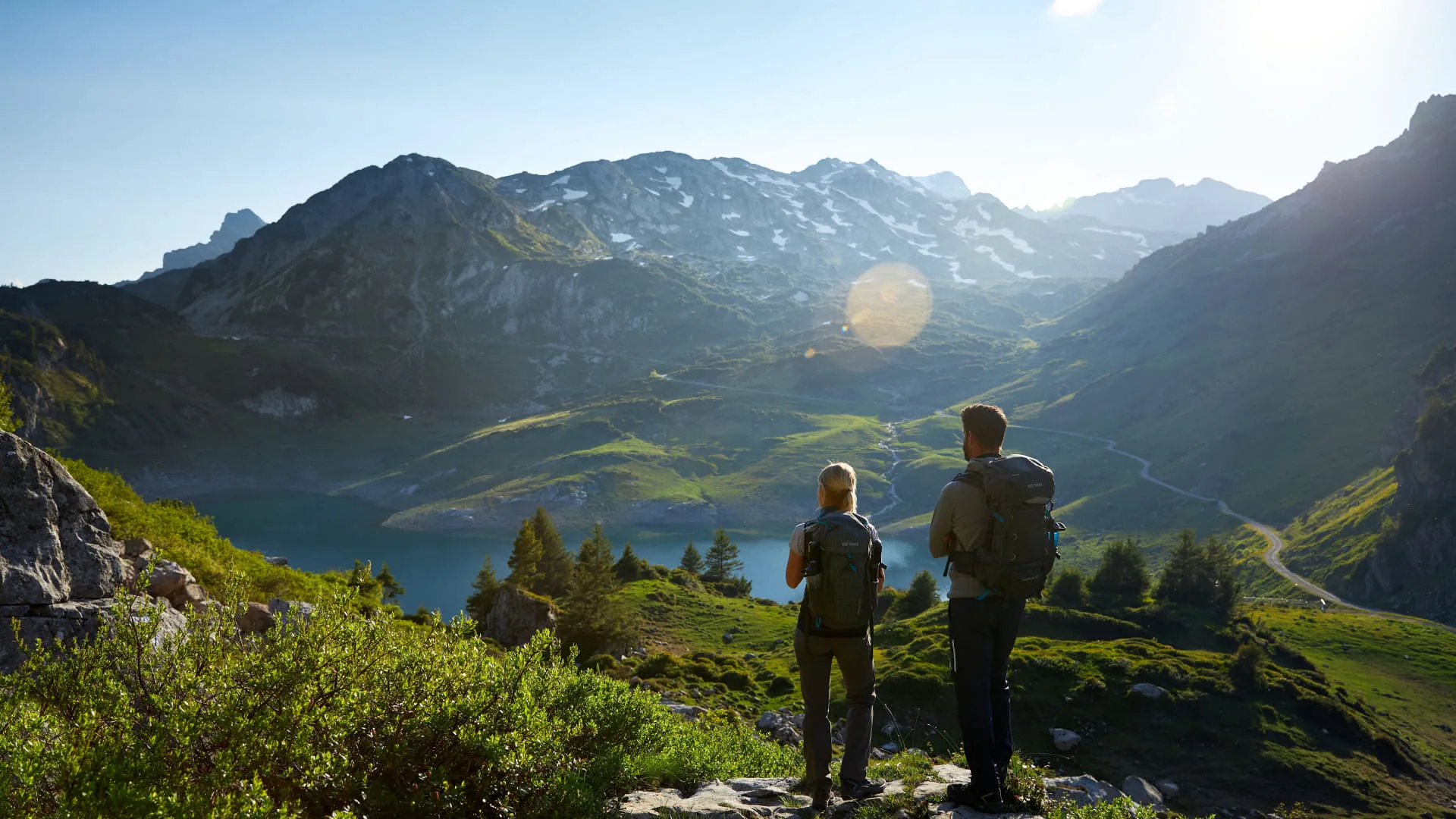 Zwei Wanderer blicken auf die Berge und ein Tal im Lechweg-Gebiet.