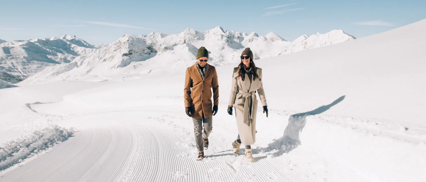 Zwei Personen wandern im Winter auf verschneitem Gelände in Lech Zürs.