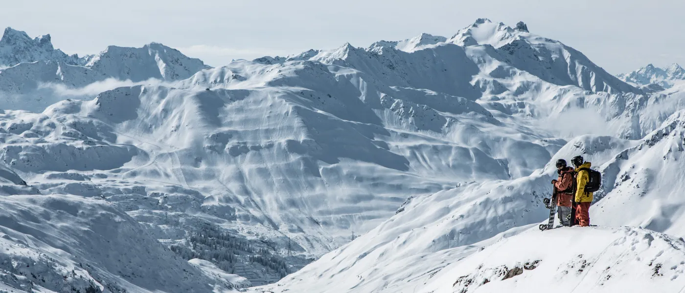 Skifahrer stehen auf einem schneebedeckten Hang in Lech-Zürs.