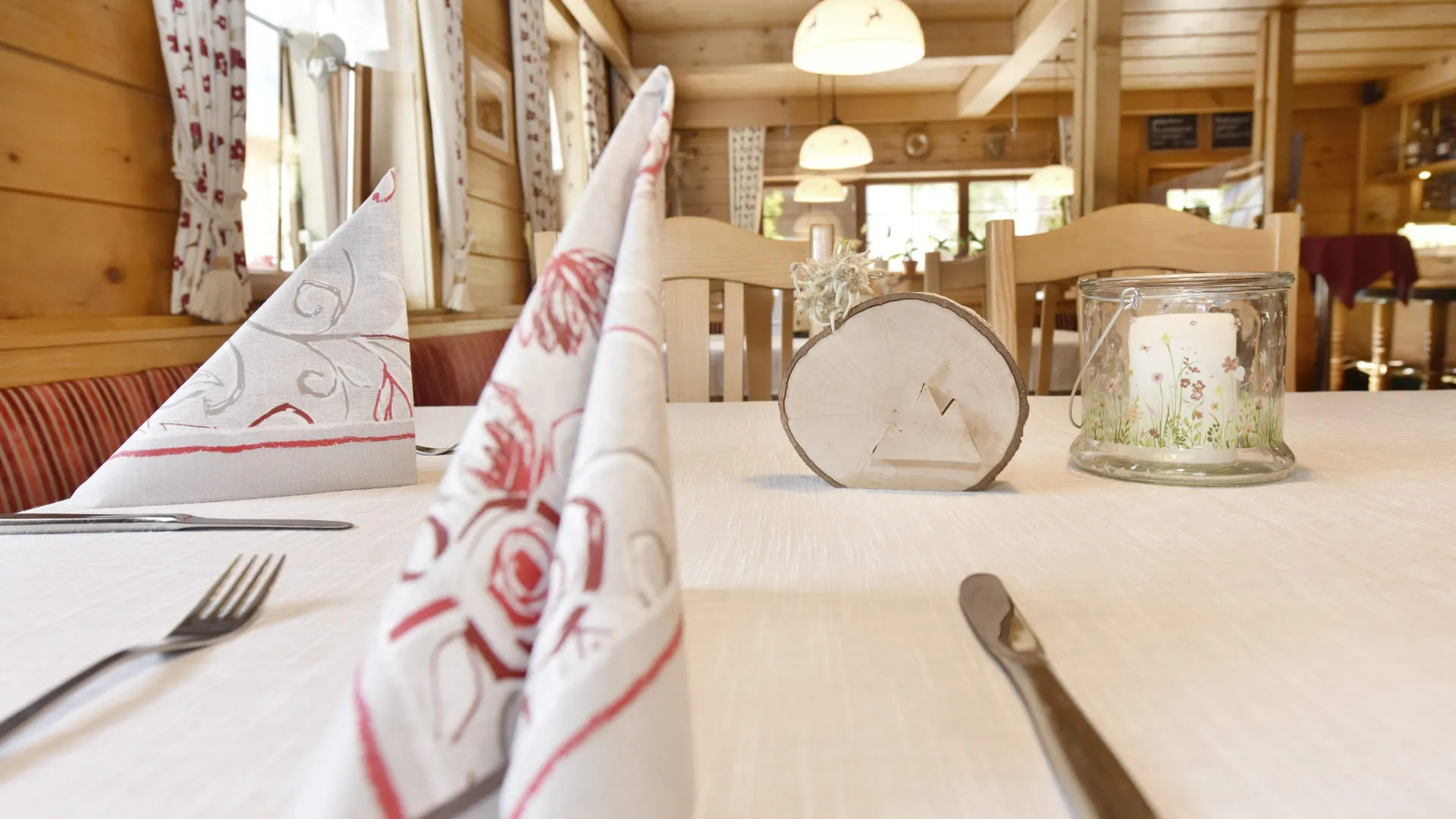 Elegant gedeckter Tisch mit Stoffservietten und Kerze in einem rustikalen Restaurant