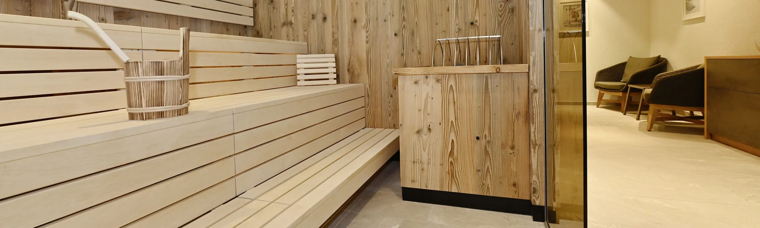 Innenansicht einer mit Holz vertäfelten Sauna mit Bänken und Sitzbereich